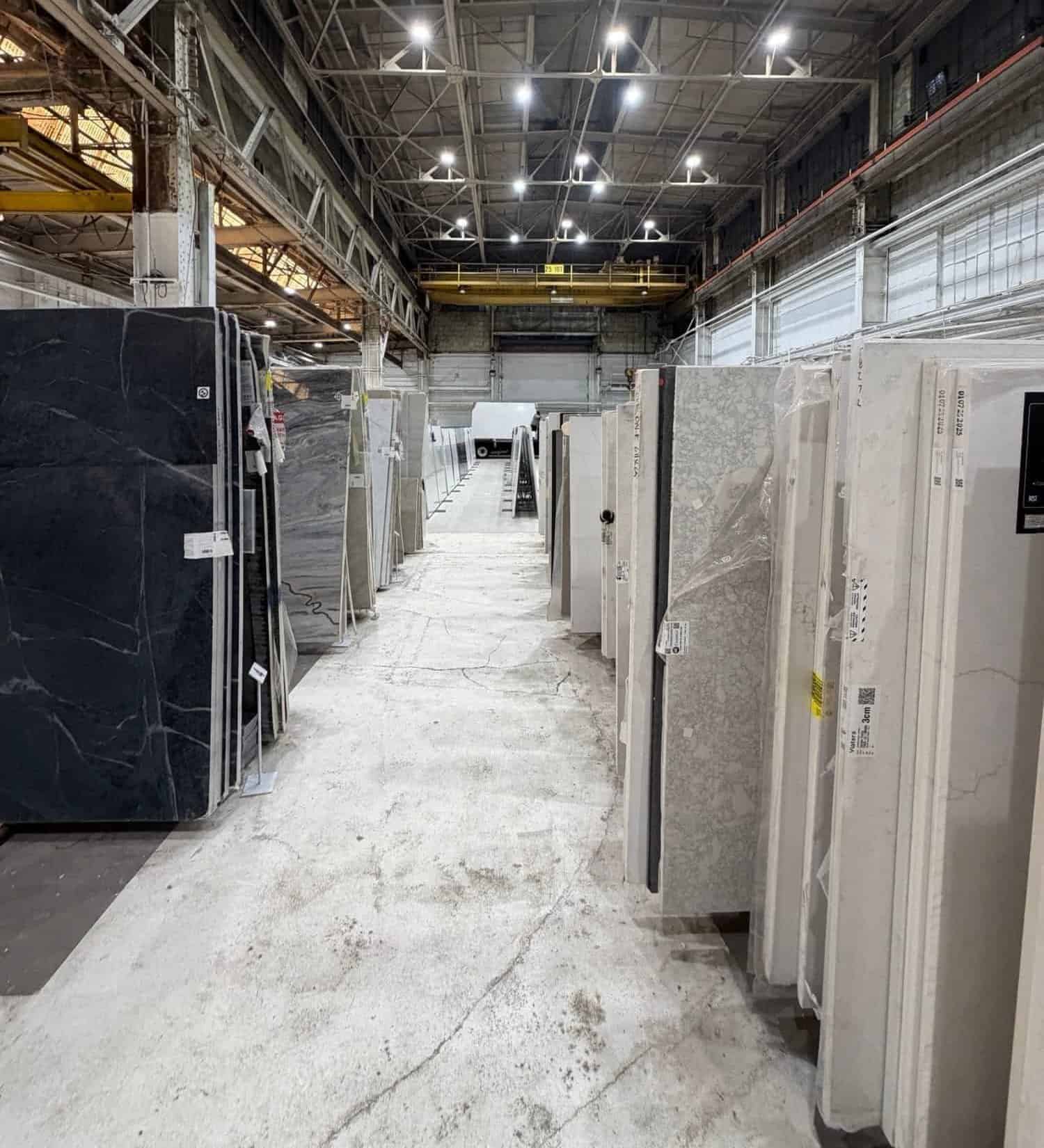 Rows of quartz and granite countertop slabs at a stone warehouse where Fedor Fabrication sources materials