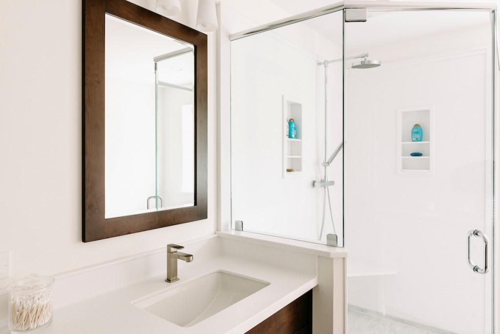 Corner sink detail in Ardmore, PA bathroom remodel — Walnut Shaker double vanity, Corian countertops, glass shower