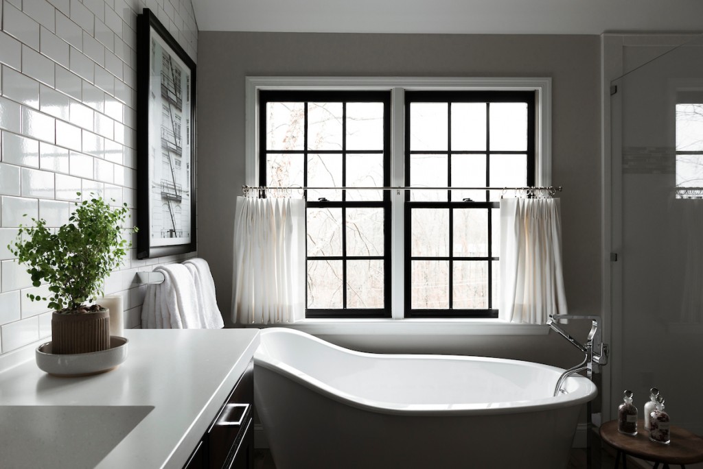Slipper tub at black-frame casement window in Berwyn, PA bathroom remodel — Espresso inset Shaker double vanity, Corian