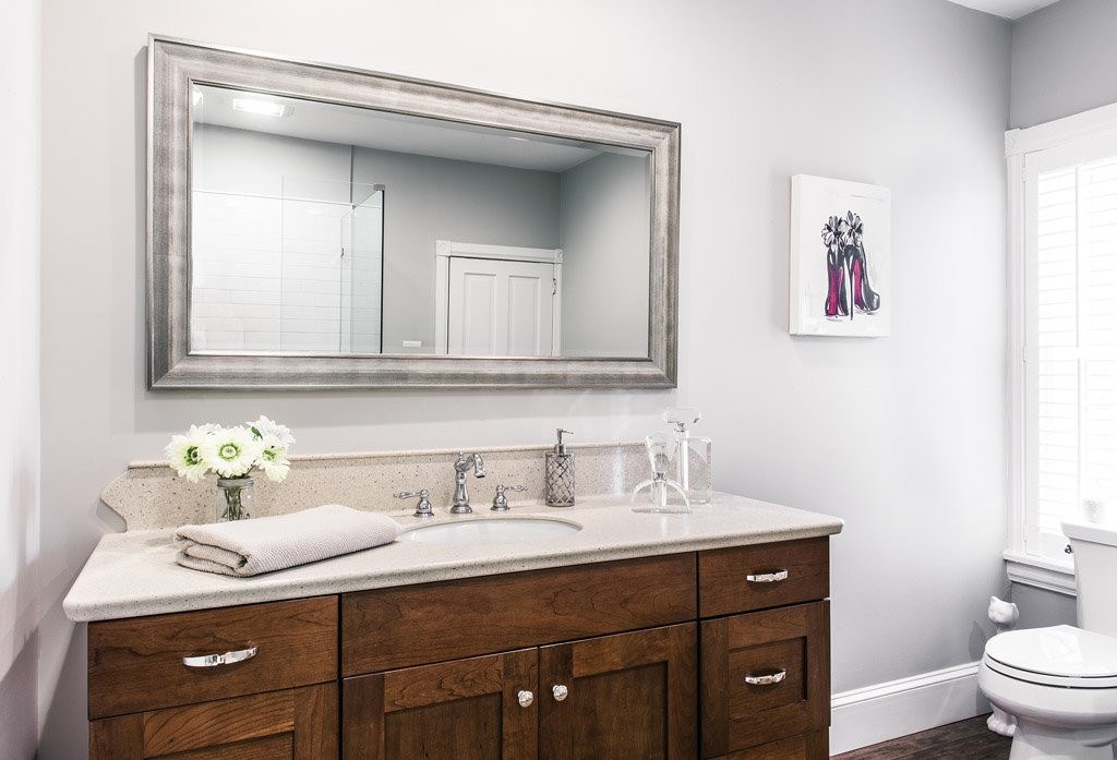 Chester Springs hall bathroom vanity with stained frameless Shaker cabinet, sandstone Corian counter, and oversized silver-leaf framed mirror