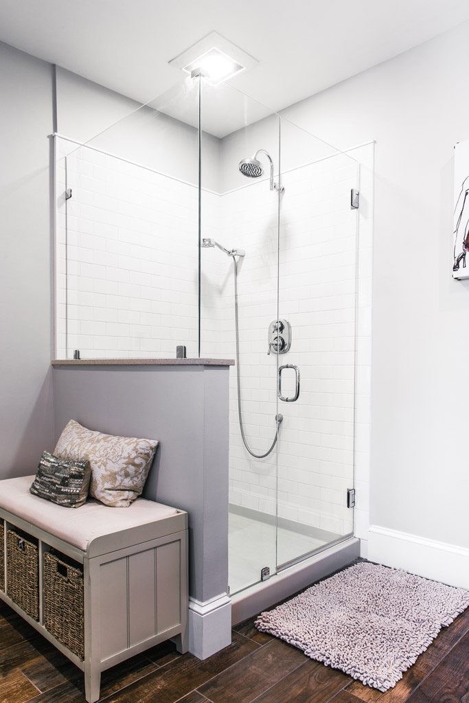 Chester Springs walk-in shower exterior view showing the frameless glass, half-wall divider with Corian cap, and built-in bench with woven basket storage