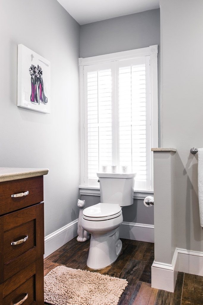 Chester Springs bathroom toilet alcove with white plantation shutter, light grey walls, and dark wood-look porcelain plank floor
