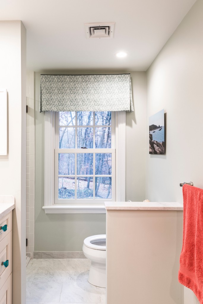 Downingtown bathroom remodel vertical view — patterned window valance, toilet alcove behind half-wall, marble floor
