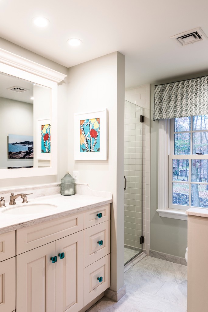 Cream Shaker vanity with frameless glass shower beyond in Downingtown, PA bathroom remodel — Cream raised-panel vanity