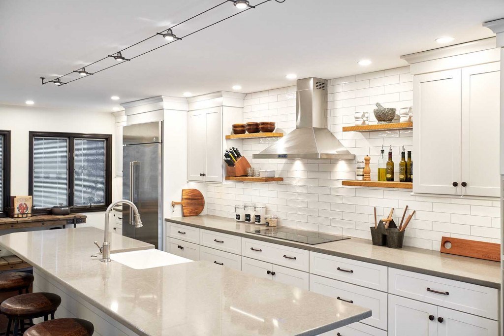 Scandinavian-style kitchen with white Shaker frameless cabinets, ebony-stained hardwood floors, black-trimmed casement windows, and a fireclay farmhouse sink on the island in Exton, PA — kitchen remodel by Fedor Fabrication