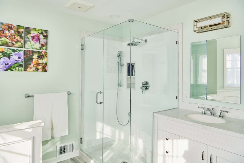 Frameless glass shower beside white painted Shaker vanity in Malvern, PA bathroom remodel — Mint primary bath