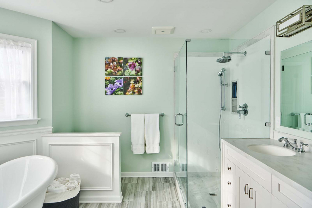 White Shaker cabinetry double vanity with freestanding slipper tub and raised-panel wainscot in Malvern, PA — primary bath remodel by Fedor Fabrication