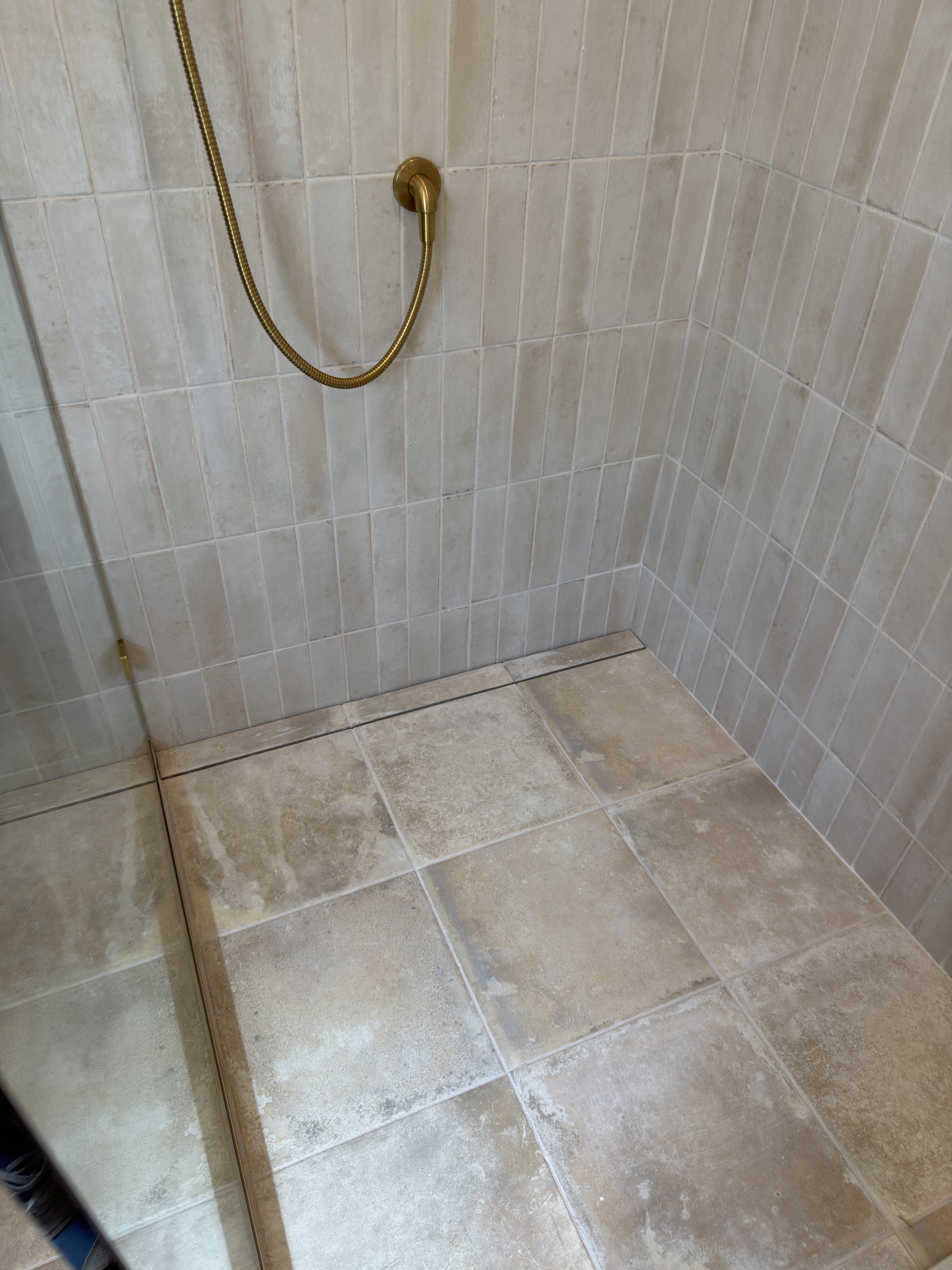 Walk-in shower floor with a linear drain and stone-look tile