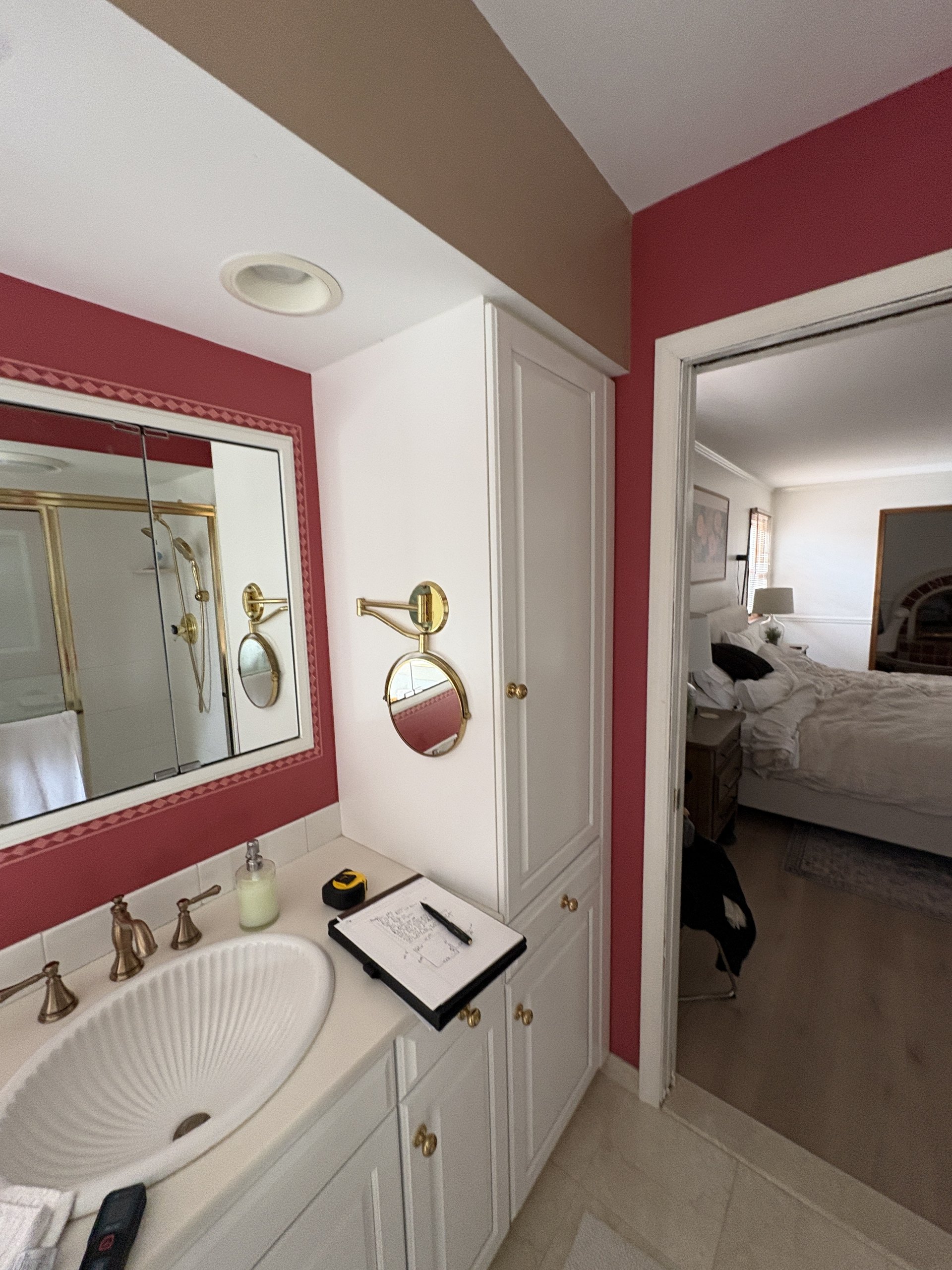 Original vanity with a shell sink, gold mirror, and mauve walls before the gut