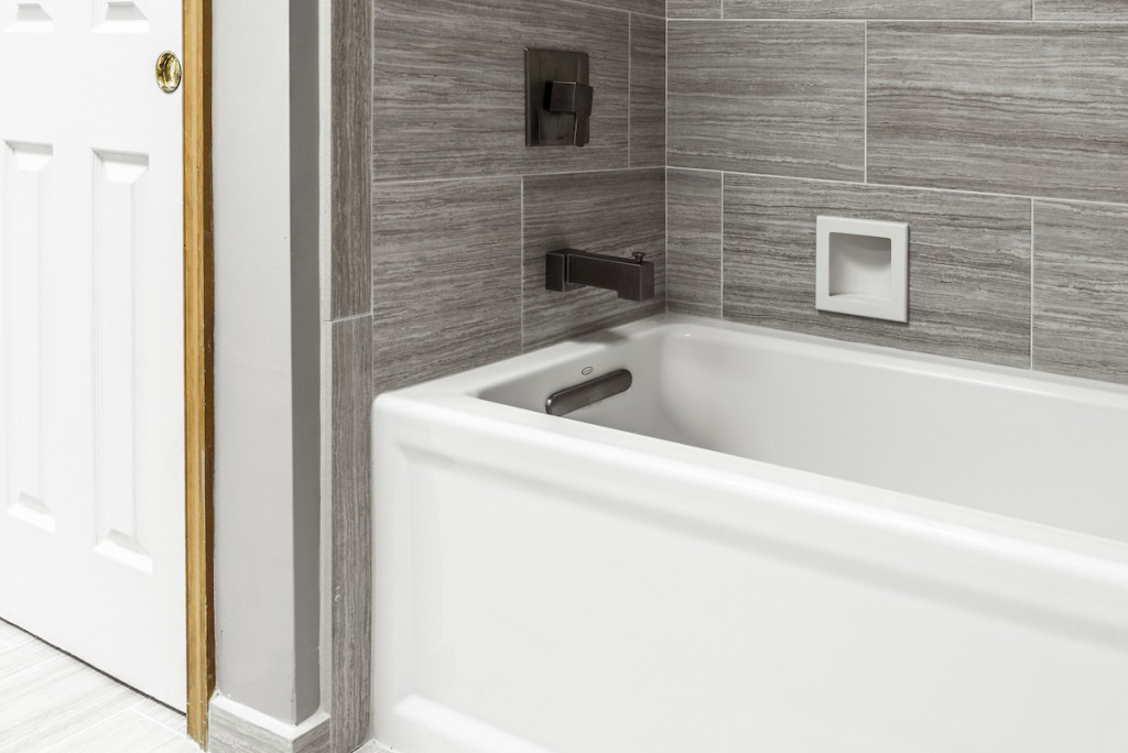 Alcove tub with gray plank-tile surround and recessed niche in Media, PA bathroom remodel — Espresso Shaker vanity