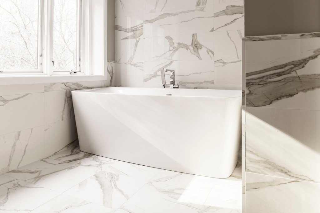 Modern angular freestanding soaker tub in Wayne, PA bathroom remodel — Quiet luxury master bath in Calacatta-look large-slab porcelain