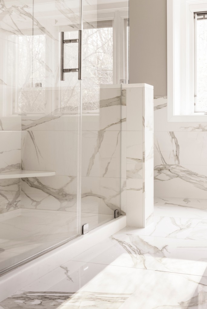 Frameless glass shower with porcelain floor vertical view in Wayne, PA bathroom remodel — Quiet luxury master bath in Calacatta-look large-slab porcelain