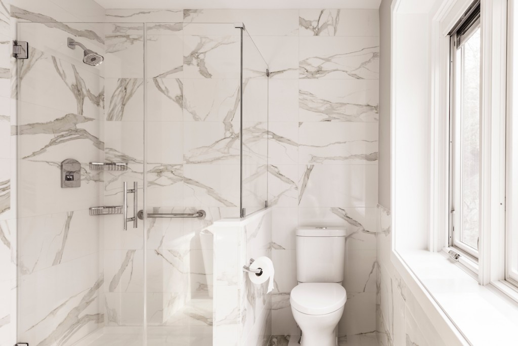 Frameless glass walk-in shower beside built-in pony wall in Wayne, PA bathroom remodel — Quiet luxury master bath in Calacatta-look large-slab porcelain