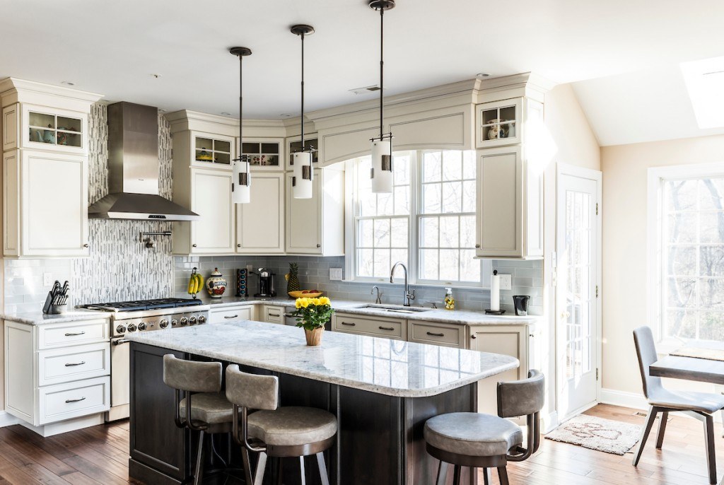 Wide view of the Wayne two-tone kitchen showing cream perimeter cabinets, espresso island, sink window, and the cathedral-ceilinged great room beyond