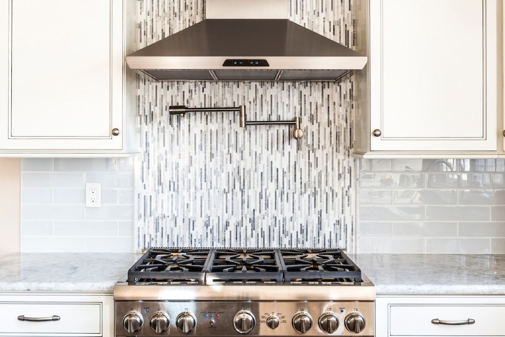 Wayne two-tone kitchen detail showing in-cabinet lighting glowing inside the glass transom uppers above the perimeter cabinets
