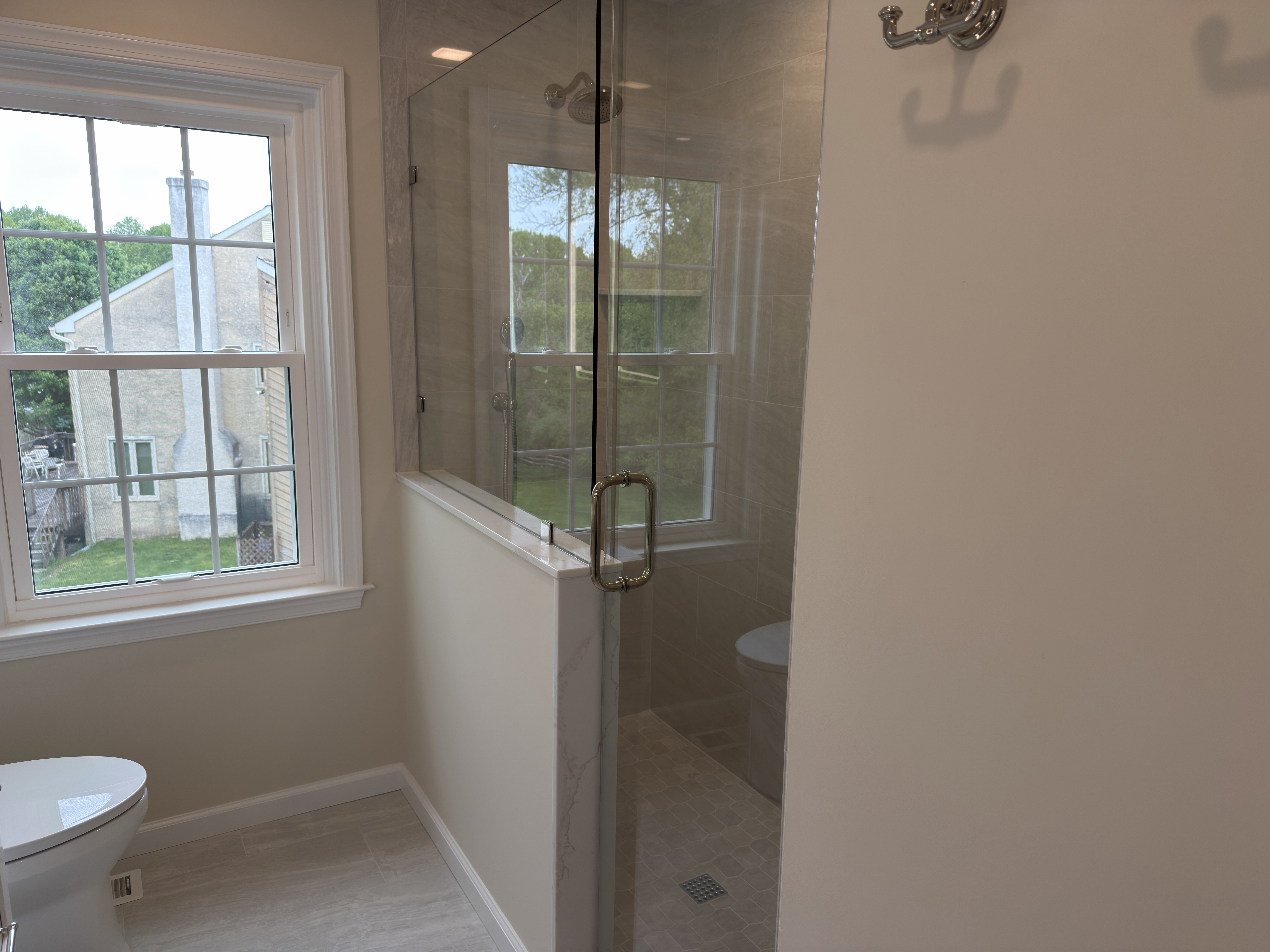 Wayne primary bathroom with half-knee-wall walk-in shower, frameless glass door, and a window inside the shower