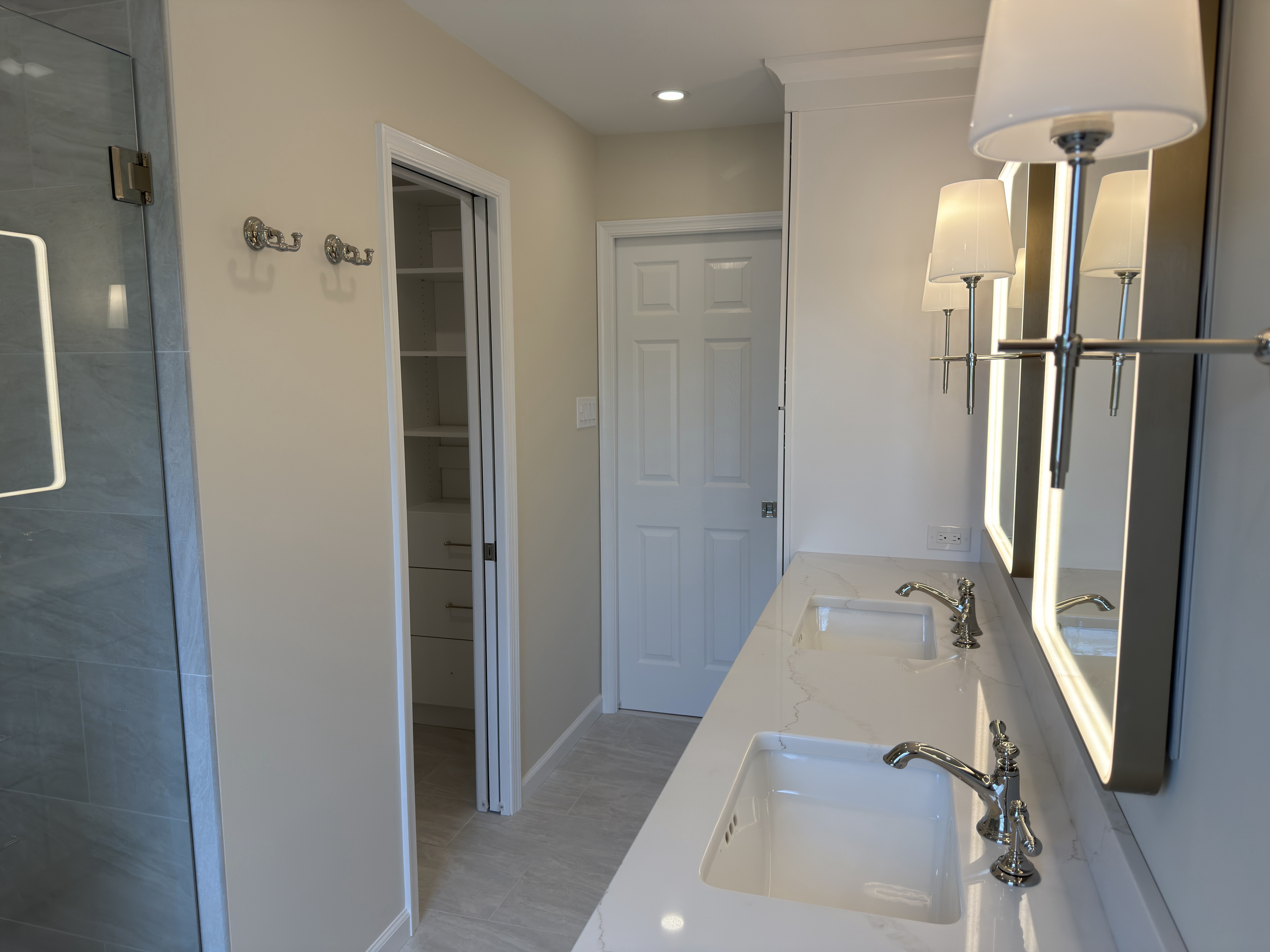 Double vanity wall from the bedroom doorway with the open pocket door into the walk-in closet visible