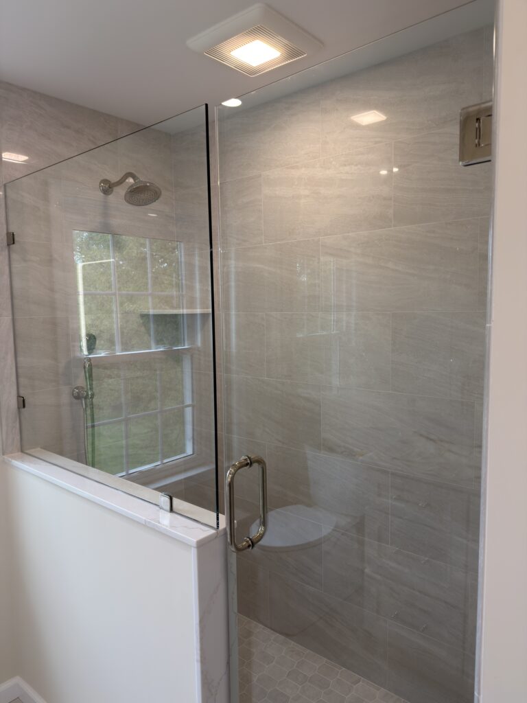 Walk-in shower rain head and handheld in polished nickel, with a corner shelf and tiled niche