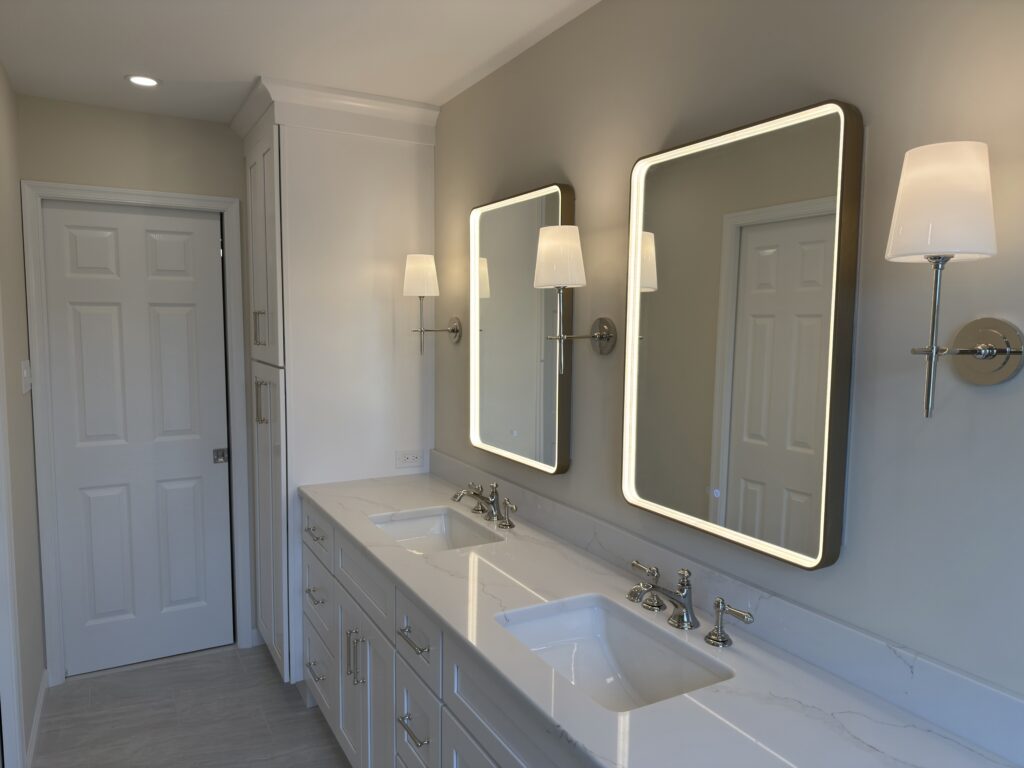 Double vanity with two LED mirrors, polished nickel sconces, and Borghini Gold quartz countertop