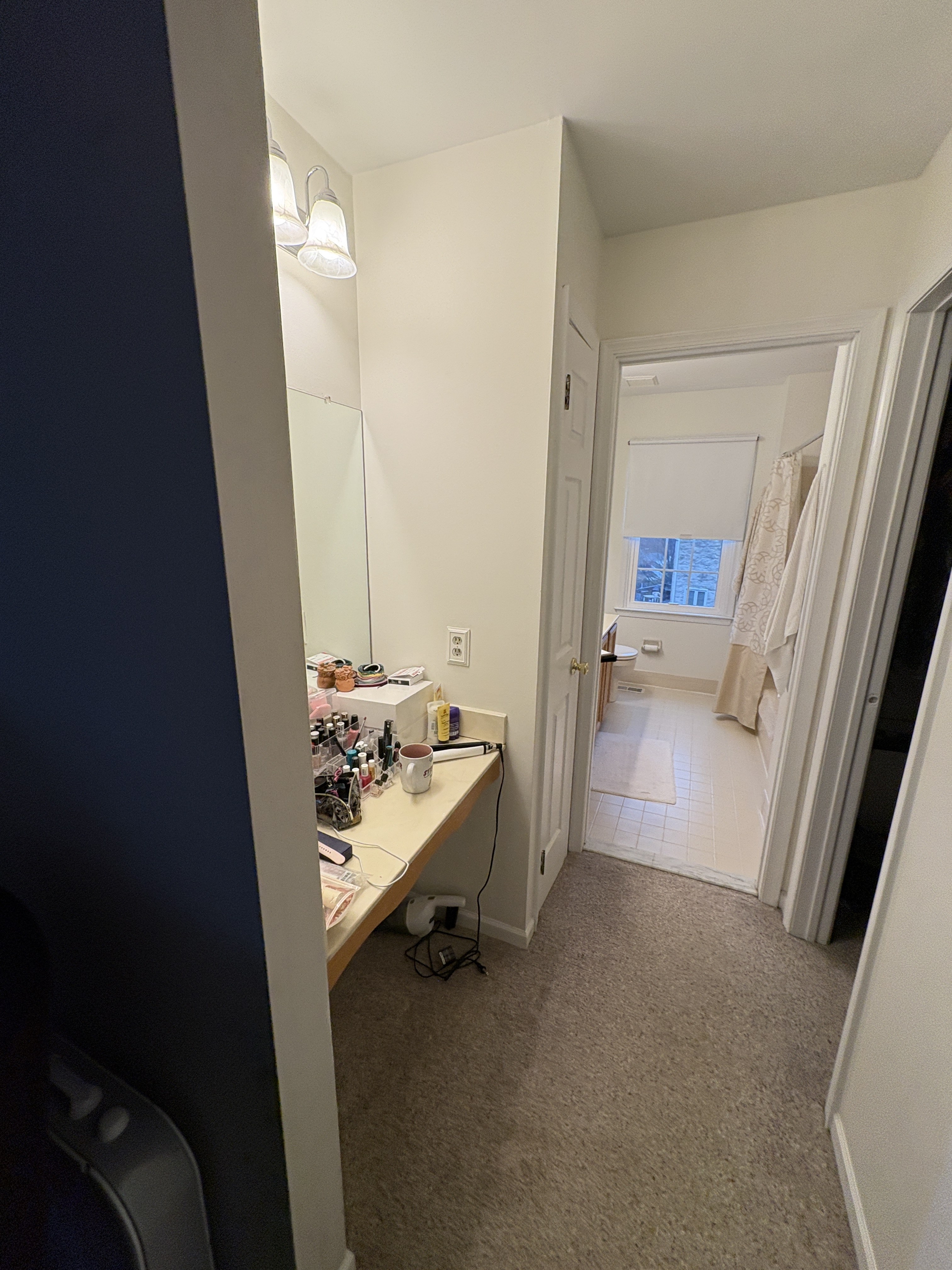 Original primary bathroom vanity area with dark blue accent wall and carpet outside the door