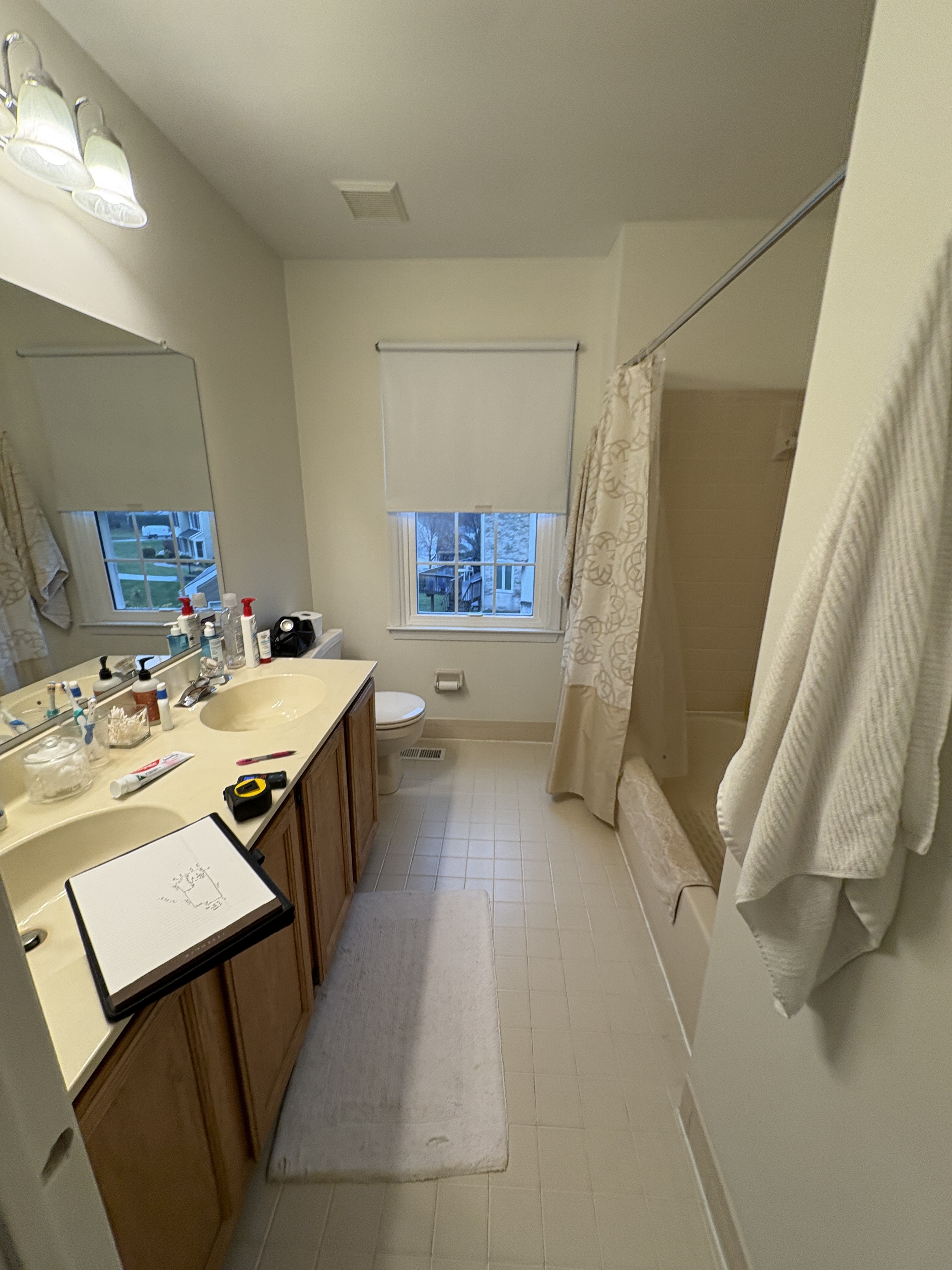 Original tub-shower combo with dated white square tile and shower curtain