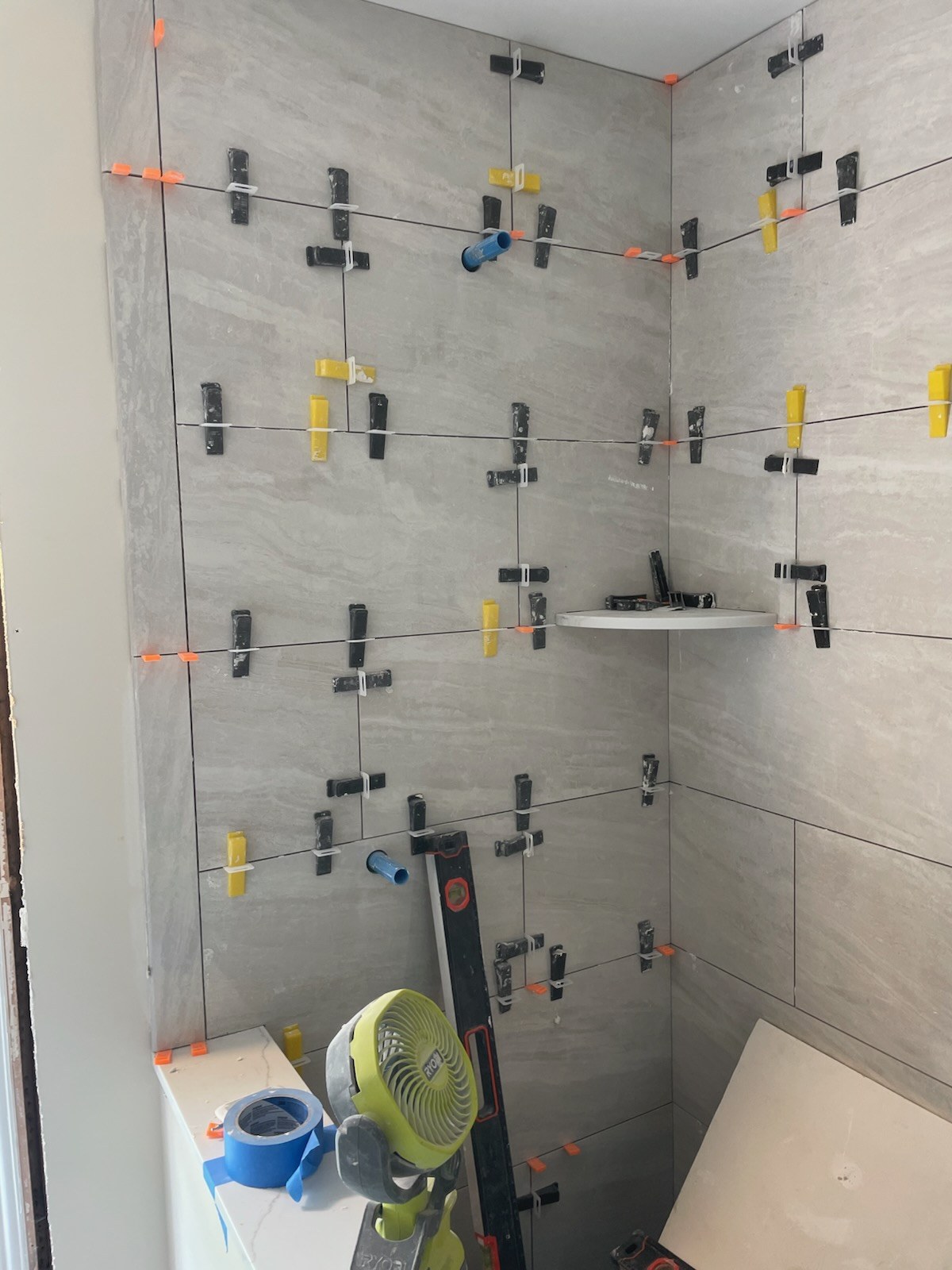 Large-format porcelain wall tile being set with leveling clips