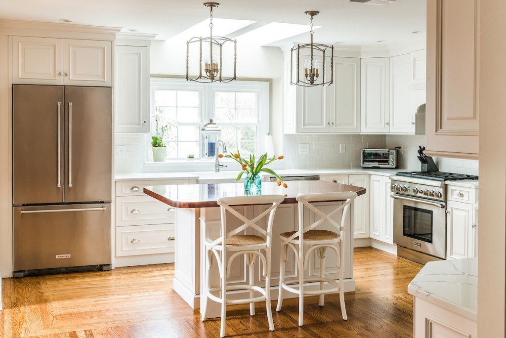 Wayne white country kitchen with raised-panel frameless cabinets, lantern pendants, stainless gas range, and butcher-block island