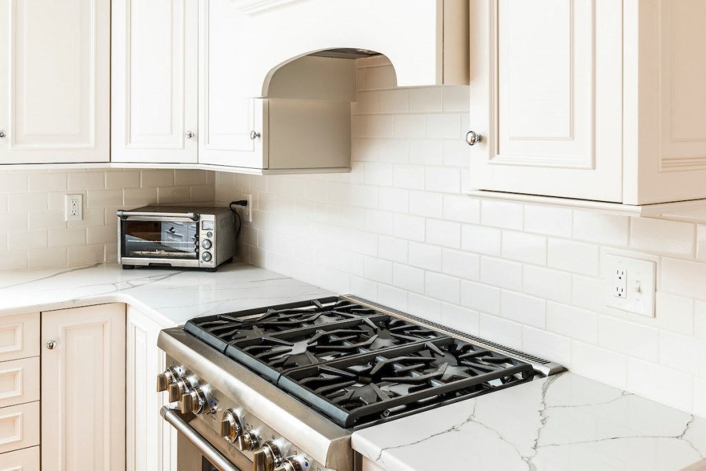 Wayne white kitchen range close-up showing Cambria quartz with bold Calacatta-style veining and the arched custom cabinet hood detail