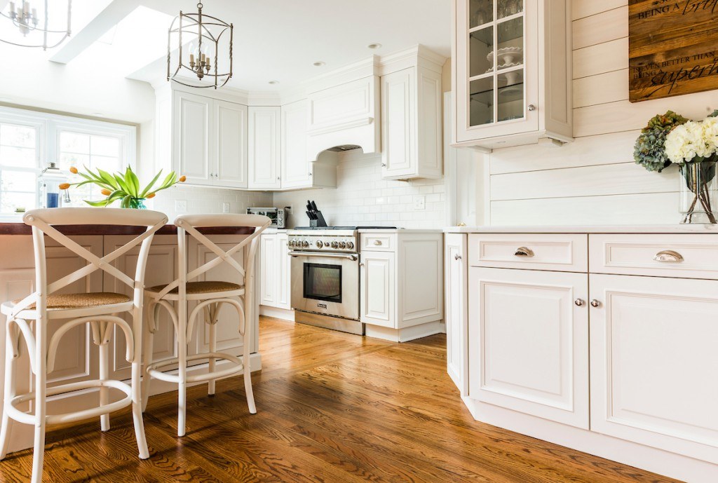 Wayne kitchen cross-back farmhouse stools at the butcher-block island, with shiplap accent wall and skylights above