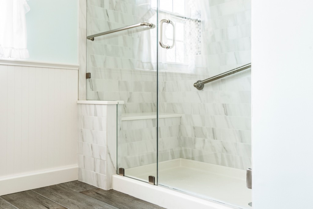 Frameless glass shower with brushed nickel grab bars in West Chester, PA bathroom remodel — Coastal seafoam primary