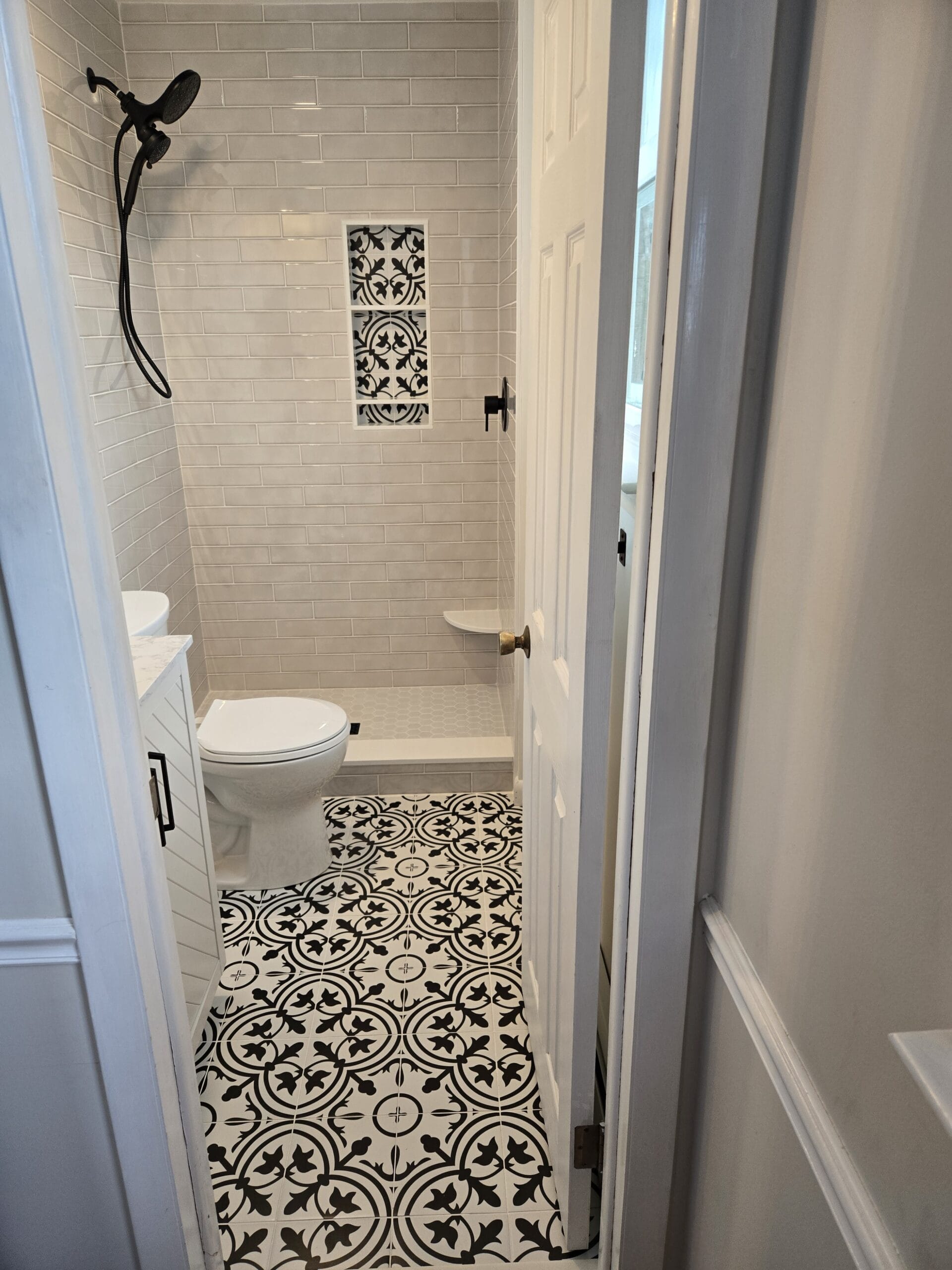 Looking into the new West Chester primary bathroom — black-and-white encaustic floor, white vertical subway shower with patterned niche, oil-rubbed bronze fixtures