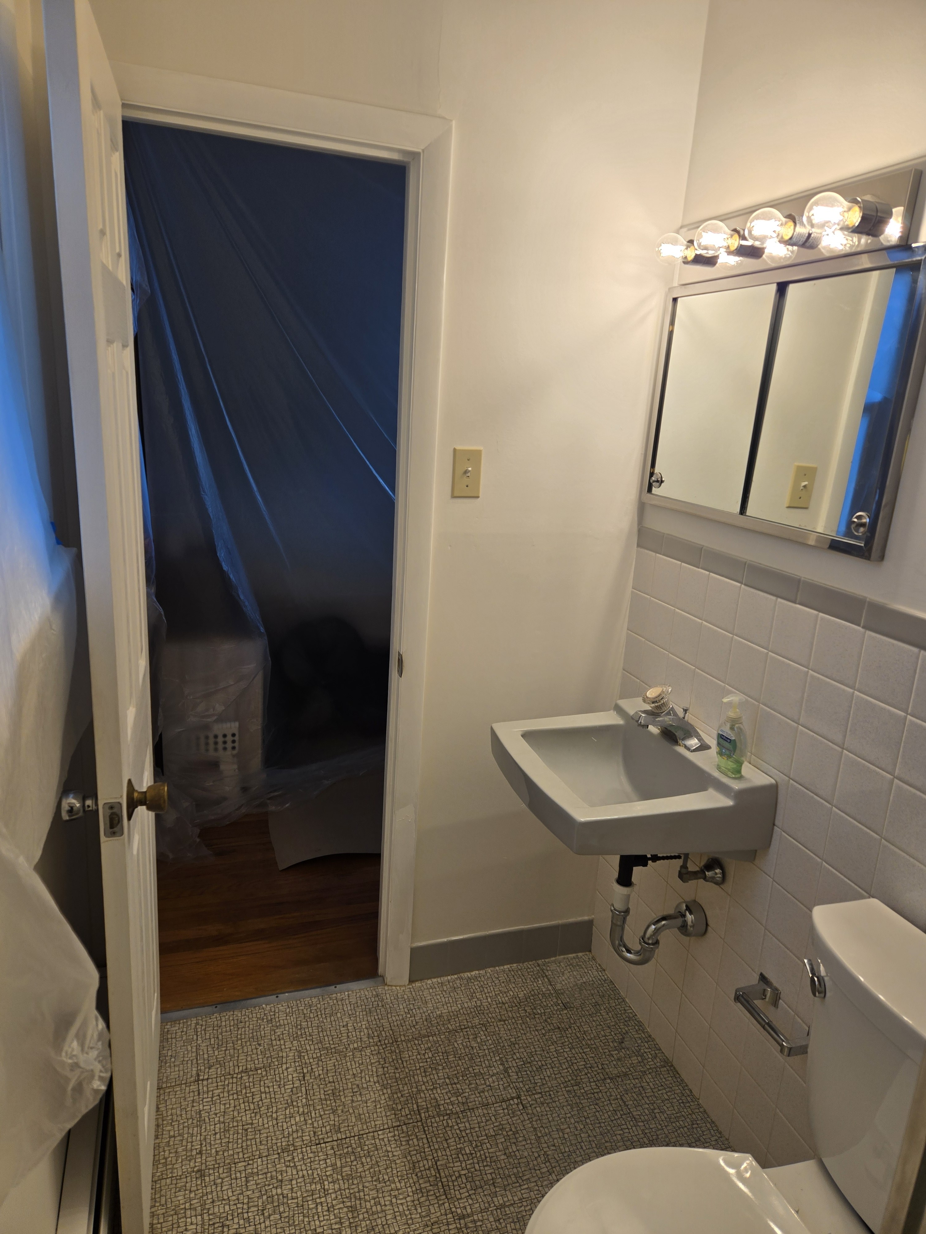 Original vanity wall — pedestal sink with exposed plumbing and Hollywood-style 4-bulb light — West Chester bathroom before remodel