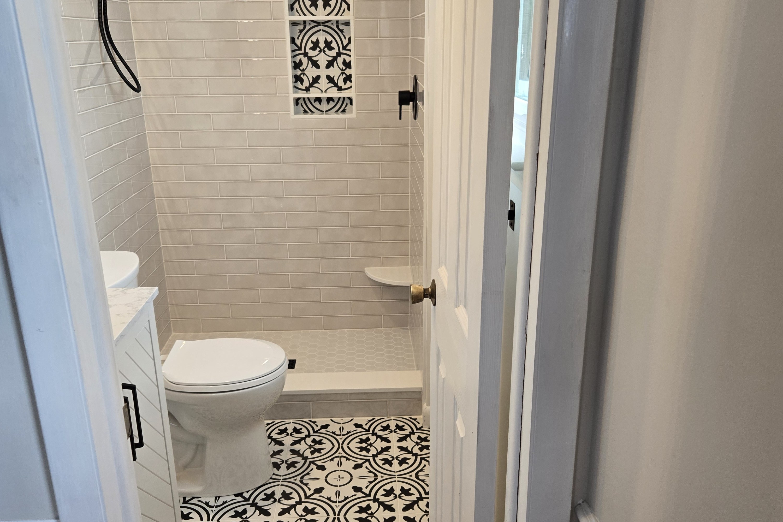 Small West Chester primary bathroom — decorative pattern floor and shower niche, white subway tile shower with matte black trim, white painted vanity — bathroom remodel by Fedor Fabrication