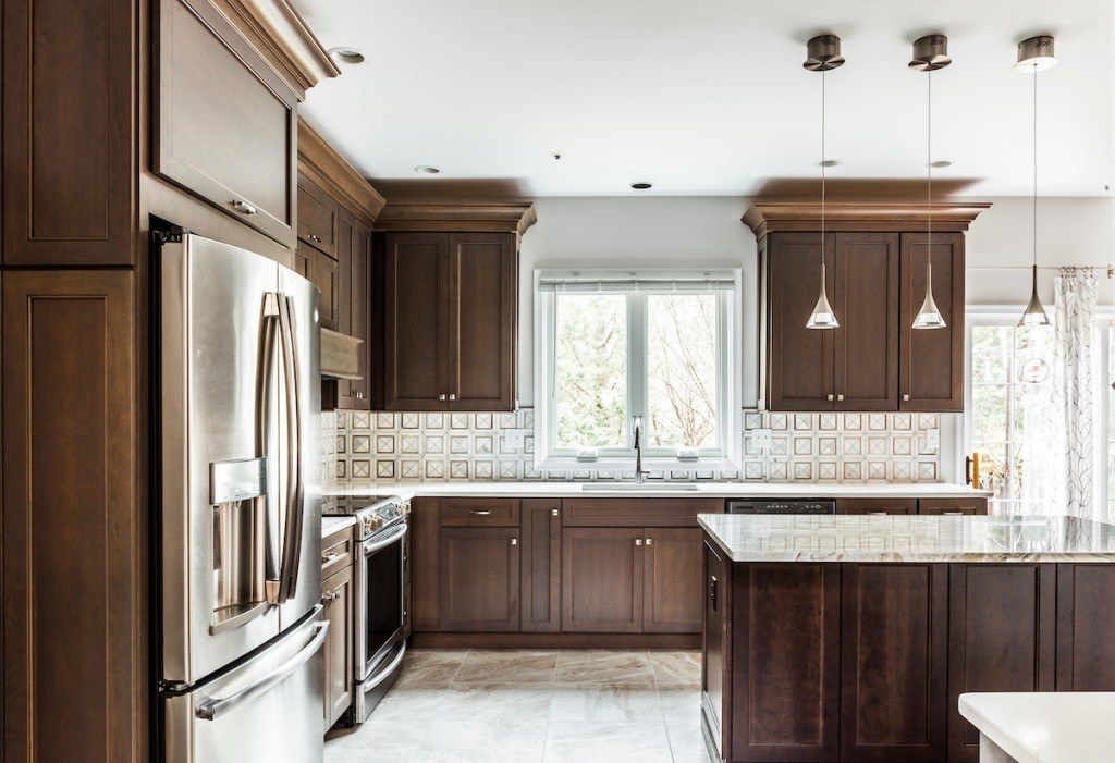 West Chester walnut kitchen view showing sink window, marble backsplash, and the stained recessed-panel cabinetry under polished nickel cup pulls
