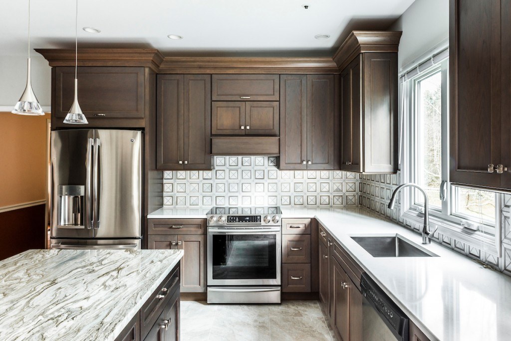 West Chester kitchen wide view with accent-quartz island in the foreground and the sculpted marble backsplash range wall beyond