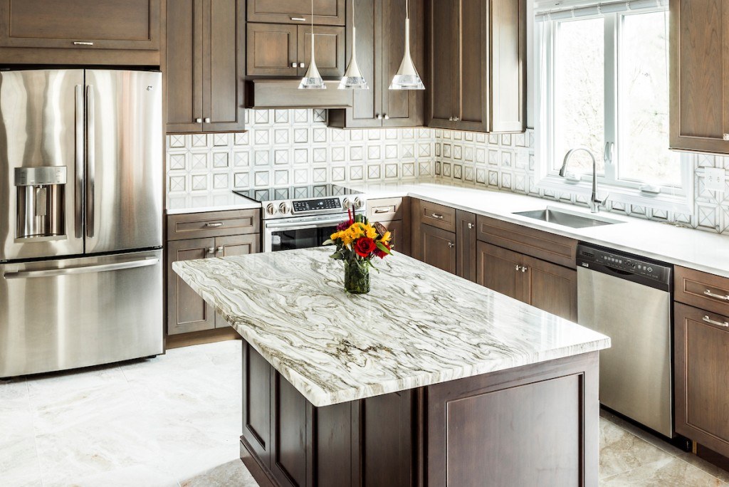 West Chester walnut kitchen showing the accent-quartz island top, polished nickel hardware, and the warm beige porcelain stone-look floor