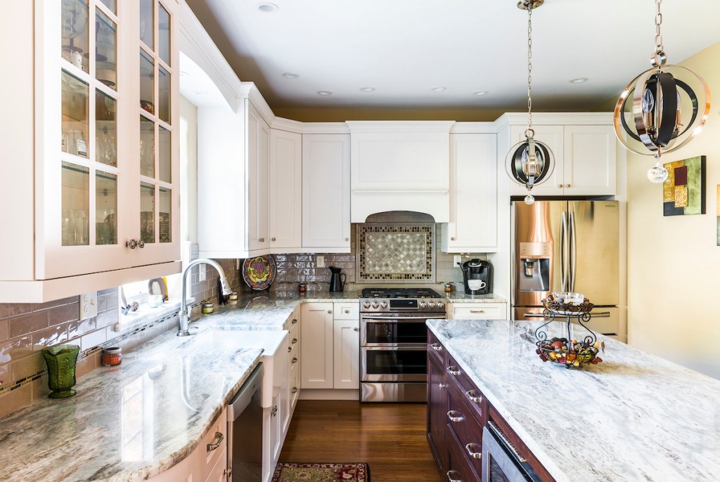 West Chester kitchen wide view from the island side showing white perimeter cabinets, dark-stained island, and silver globe pendants