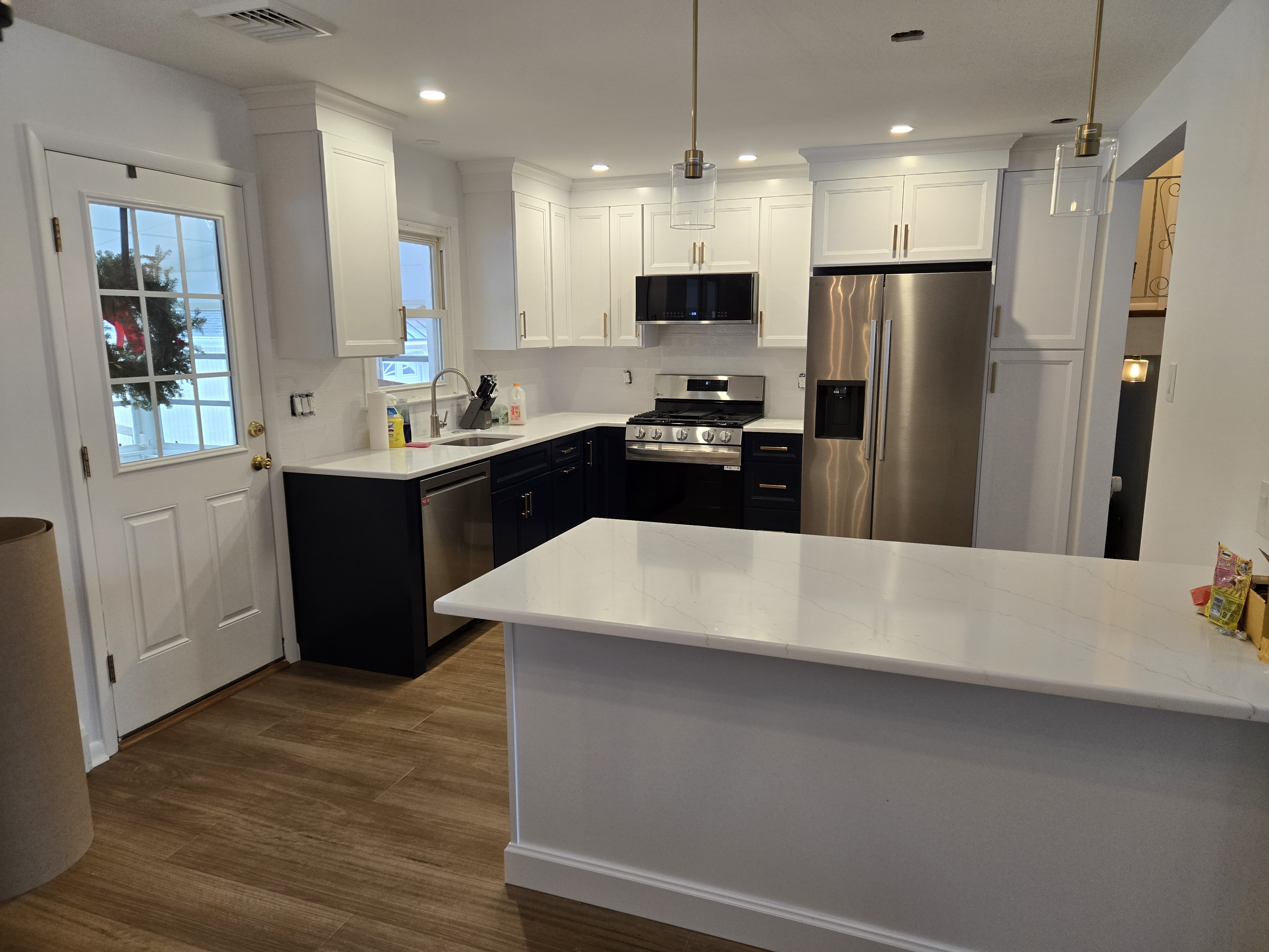 Two-tone Shaker kitchen with navy lowers, white uppers, brass pulls, and a quartz peninsula in West Chester, PA — kitchen remodel by Fedor Fabrication
