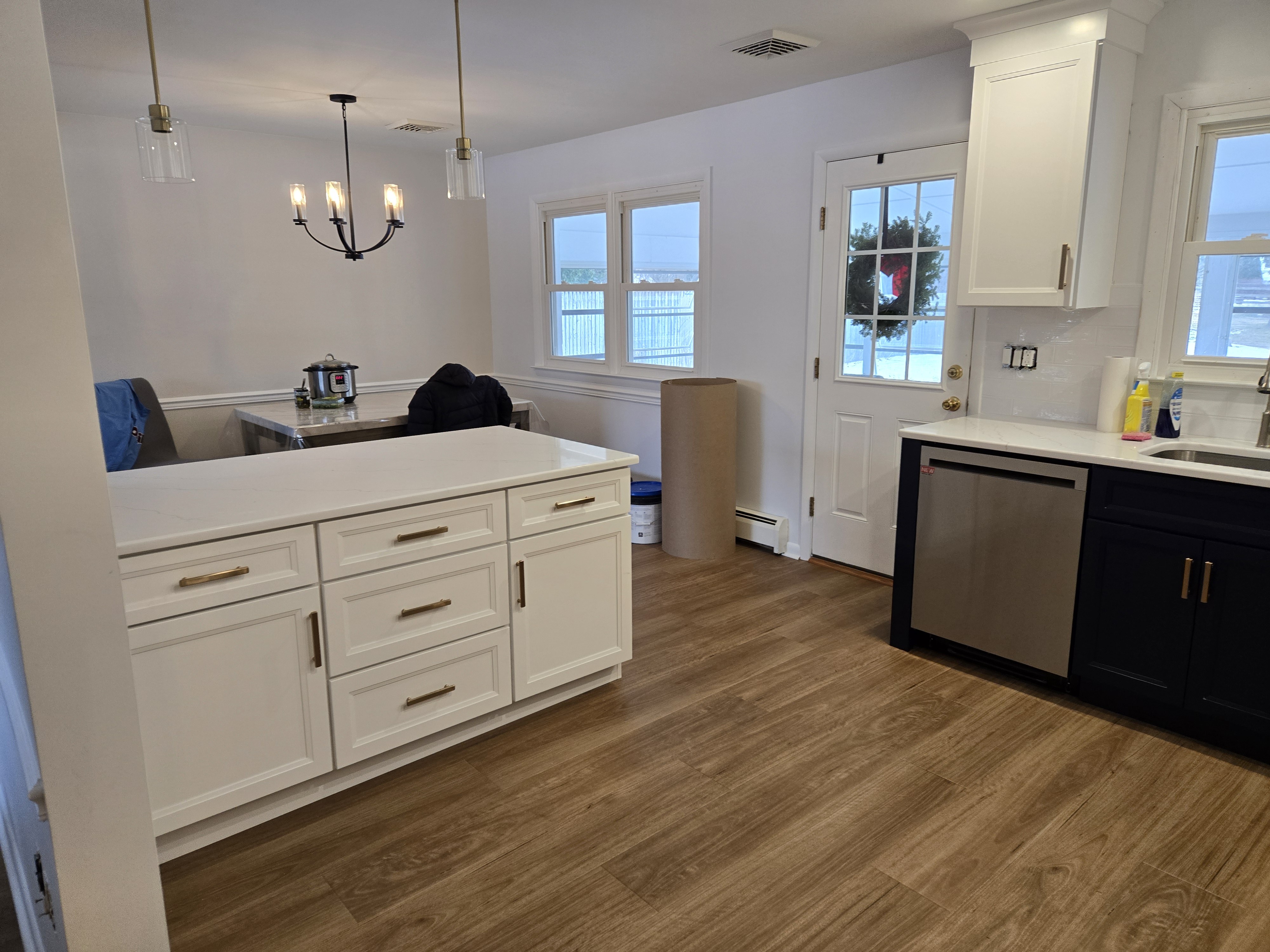 Wide angle of the finished kitchen — peninsula, dishwasher, three-light pendant chandelier — West Chester two-tone Shaker remodel
