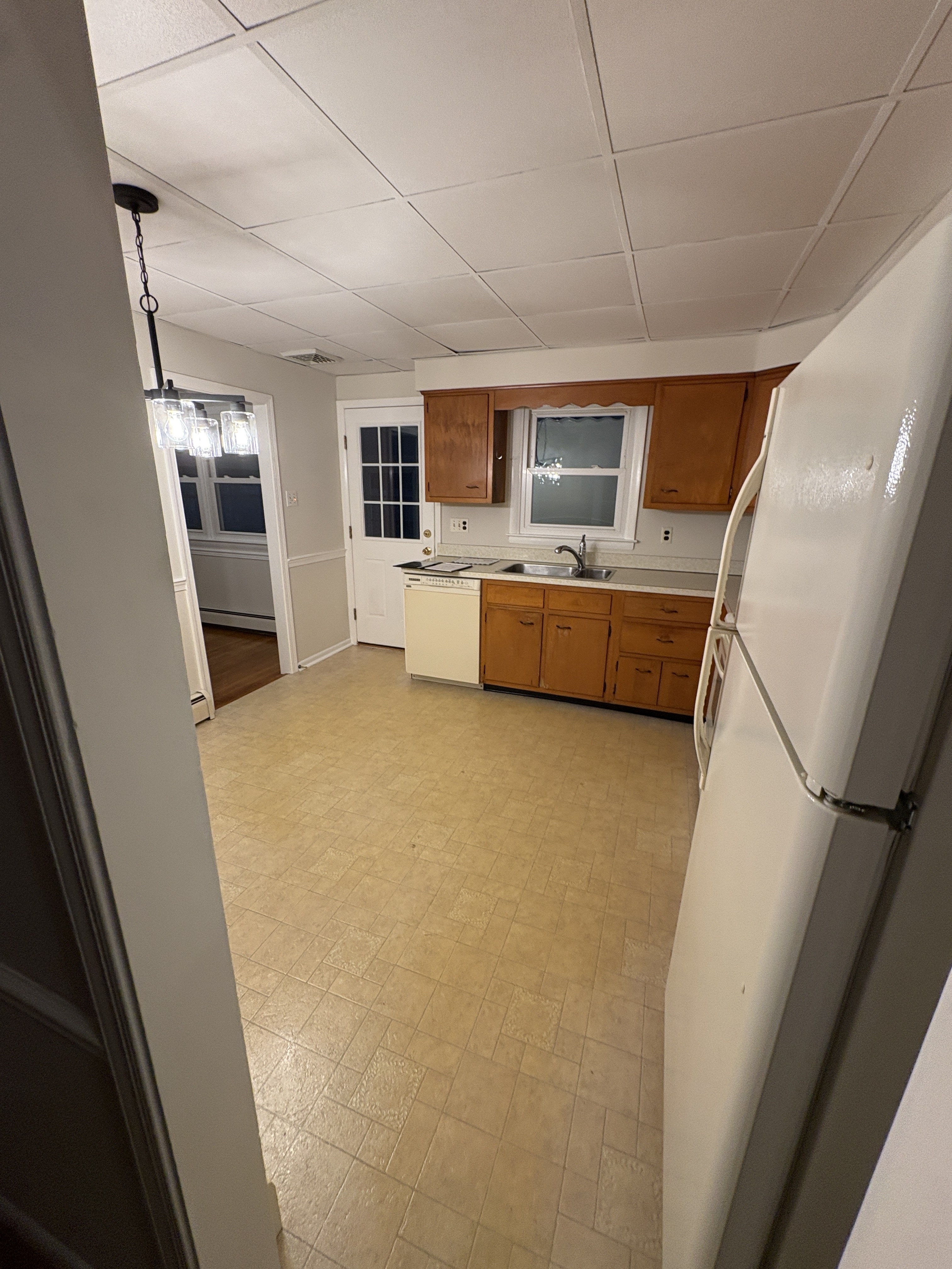 Original 1950s West Chester kitchen with drop ceiling, honey pine cabinets, white appliances, and yellow vinyl floor — before Fedor remodel