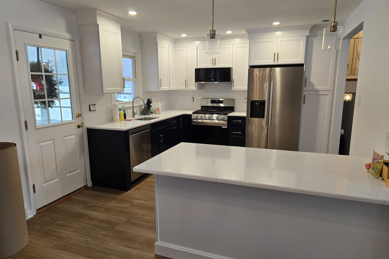 Two-tone Shaker kitchen with navy lowers, white uppers, brass pulls, and a quartz peninsula in West Chester, PA — kitchen remodel by Fedor Fabrication