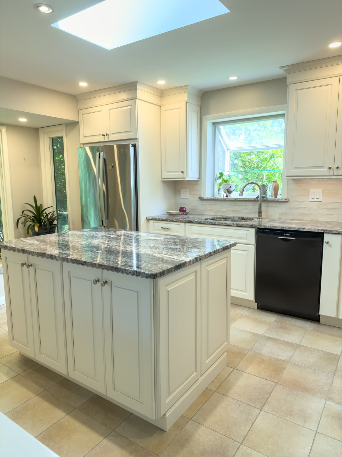 Remodeled Chester Springs kitchen island and cream cabinetry with garden window