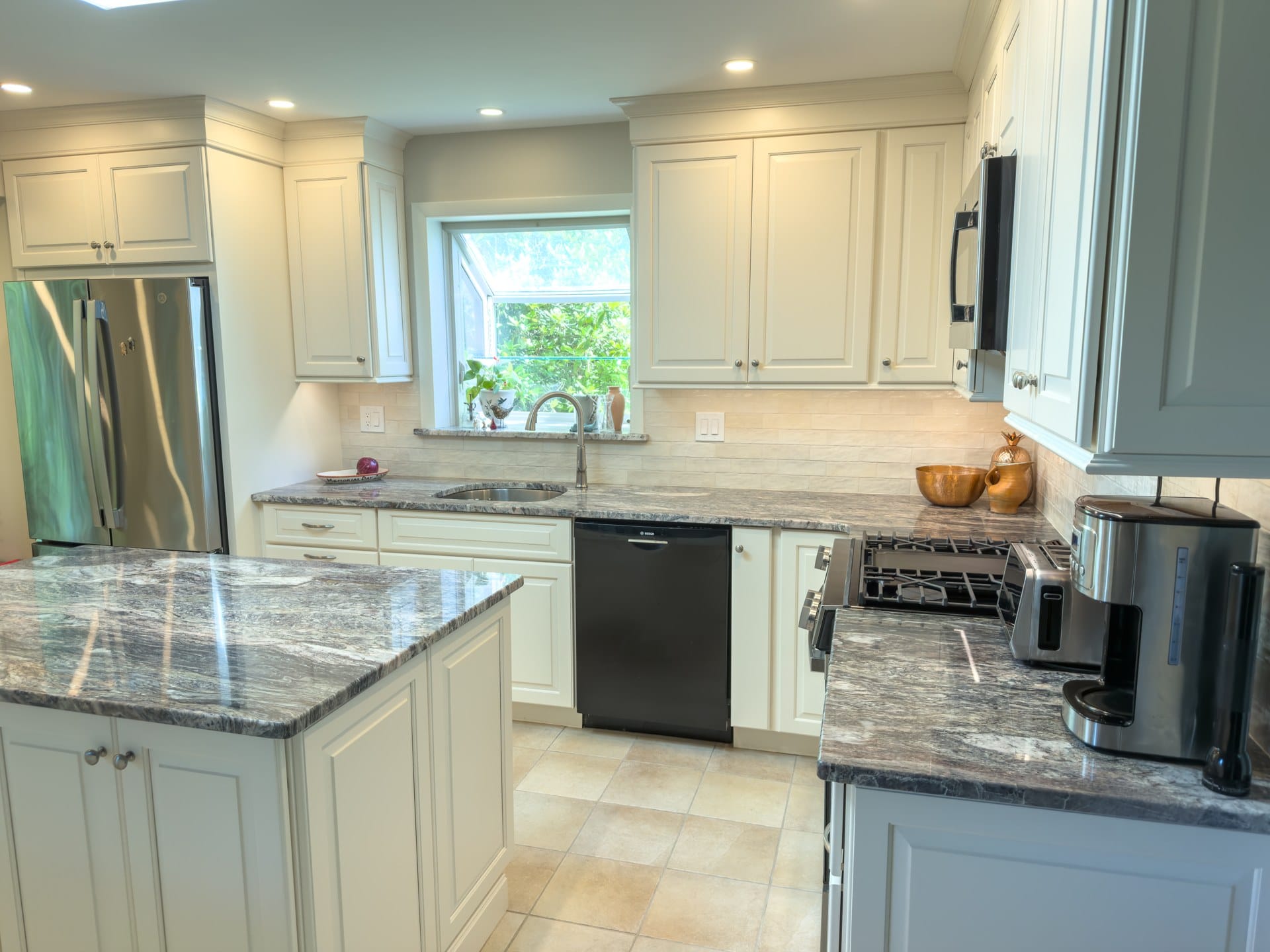 Wide view of a remodeled Chester Springs kitchen with island, garden window, and stainless appliances