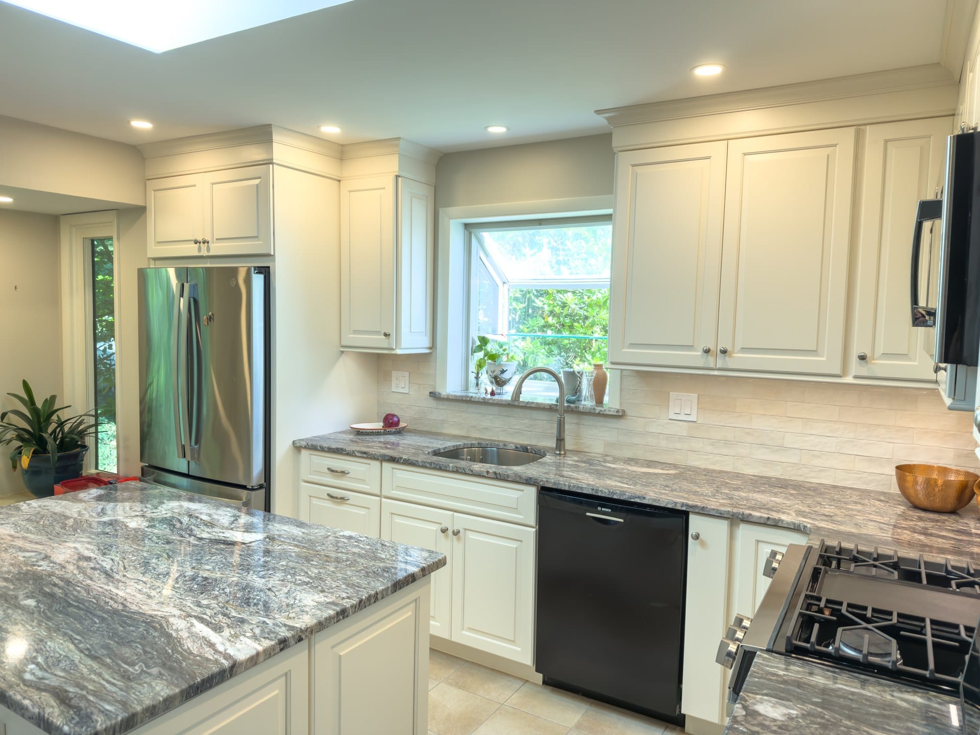 Remodeled Chester Springs kitchen with stainless refrigerator, sink under a garden window, and granite island