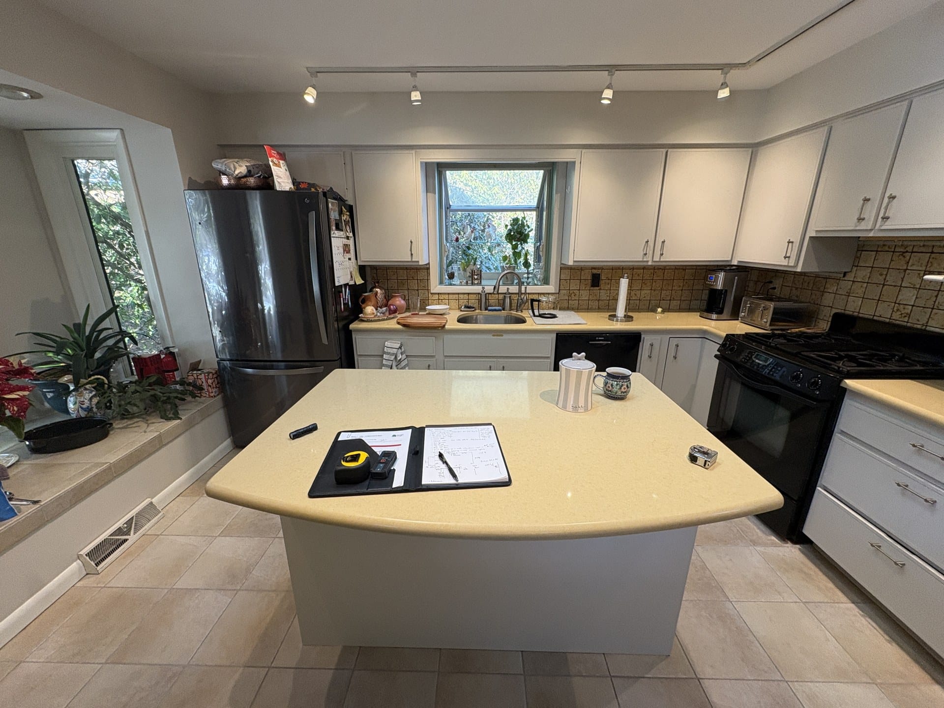 Original Chester Springs kitchen with light cabinets, solid-surface counters, and black appliances before remodel