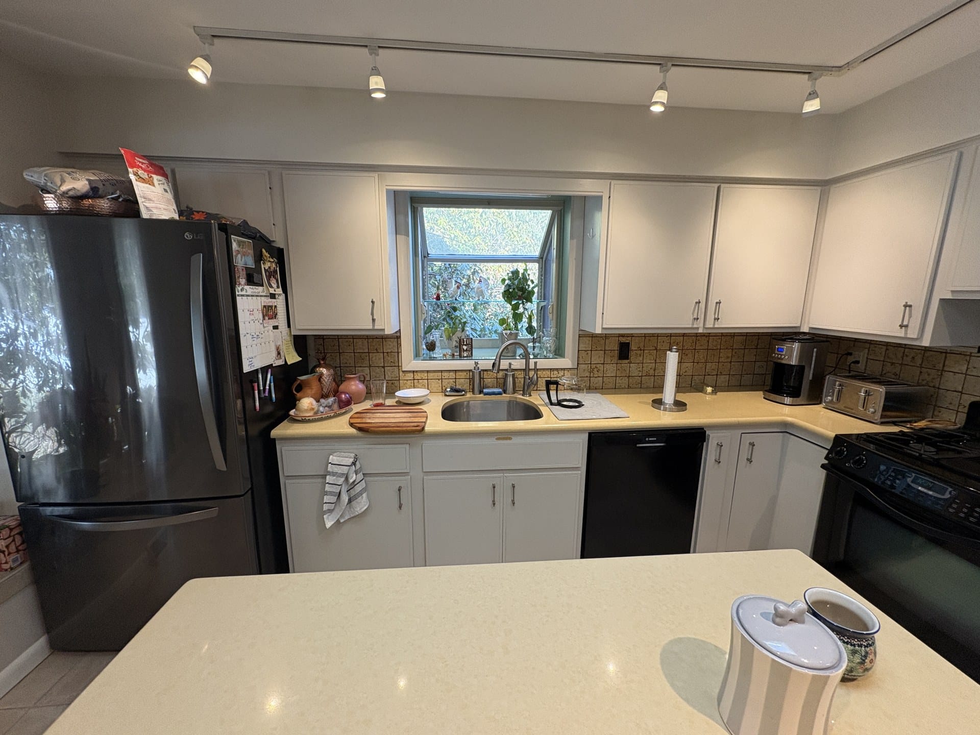 Dated Chester Springs kitchen with black refrigerator and solid-surface counters before remodel