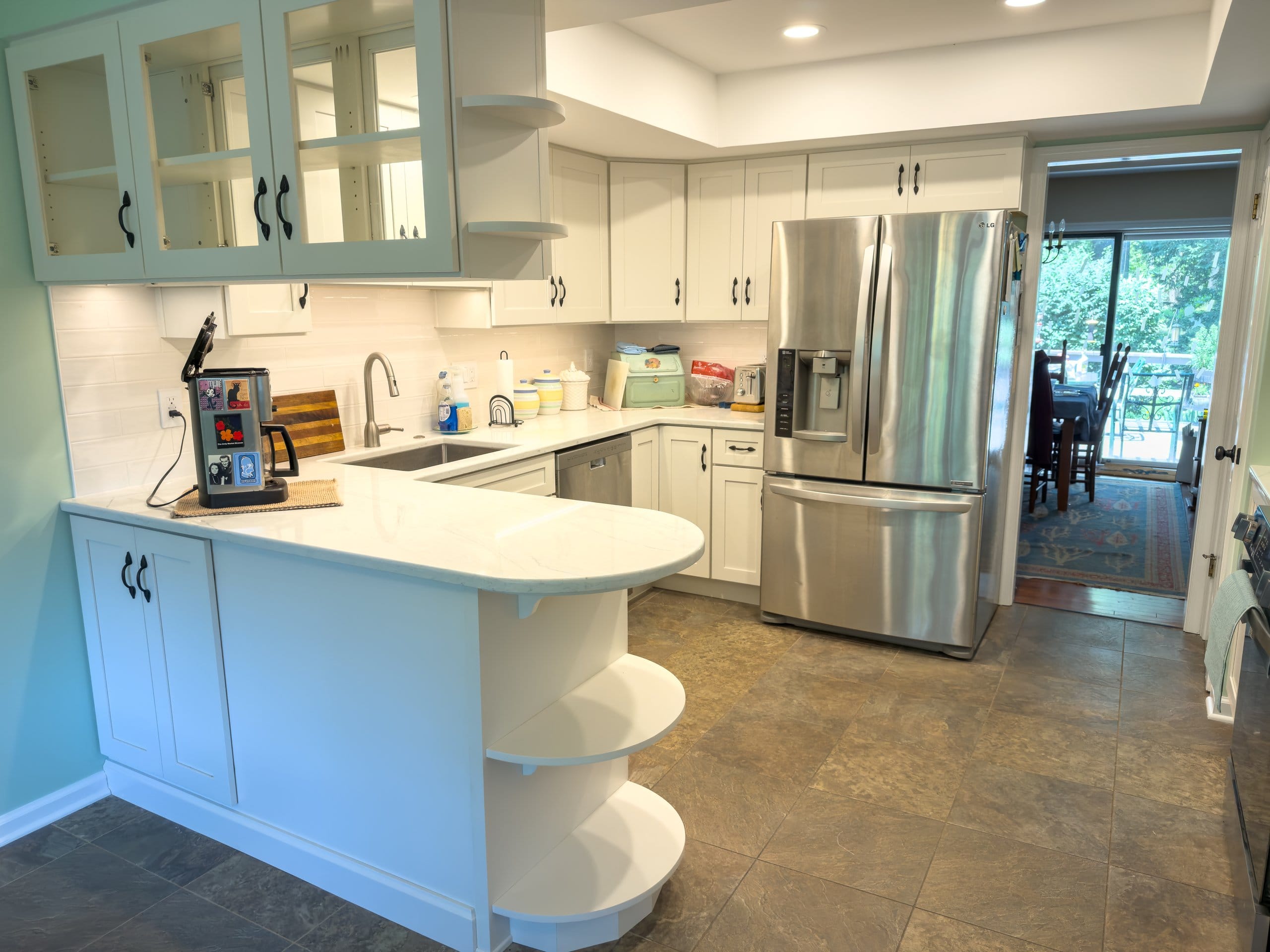 West Chester kitchen after the refresh with white Shaker cabinets, a curved peninsula with open display shelves, marble-look quartz counters, and a sage accent wall