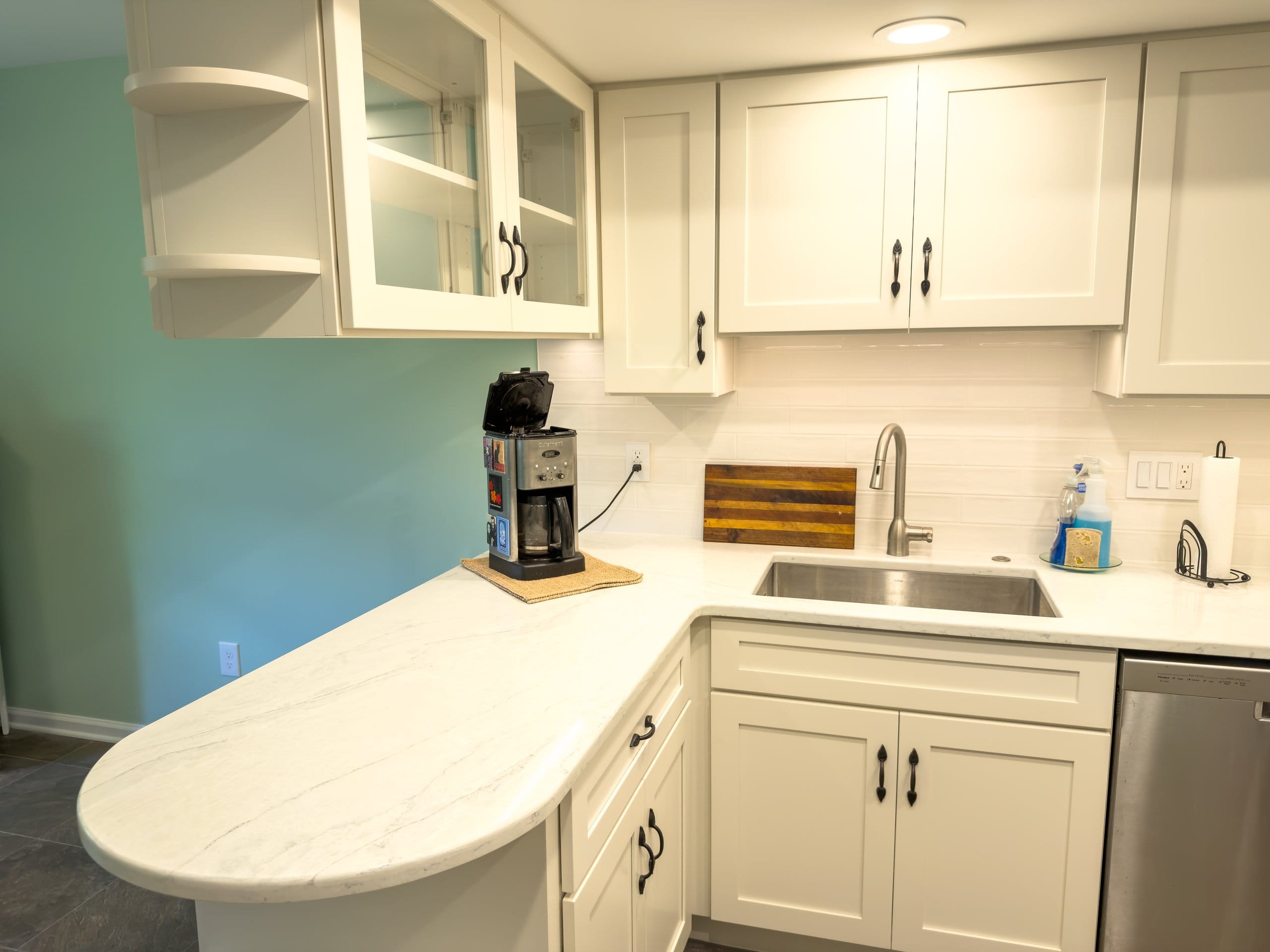 Curved peninsula and coffee station in the refreshed West Chester kitchen with white quartz and glass-front cabinets