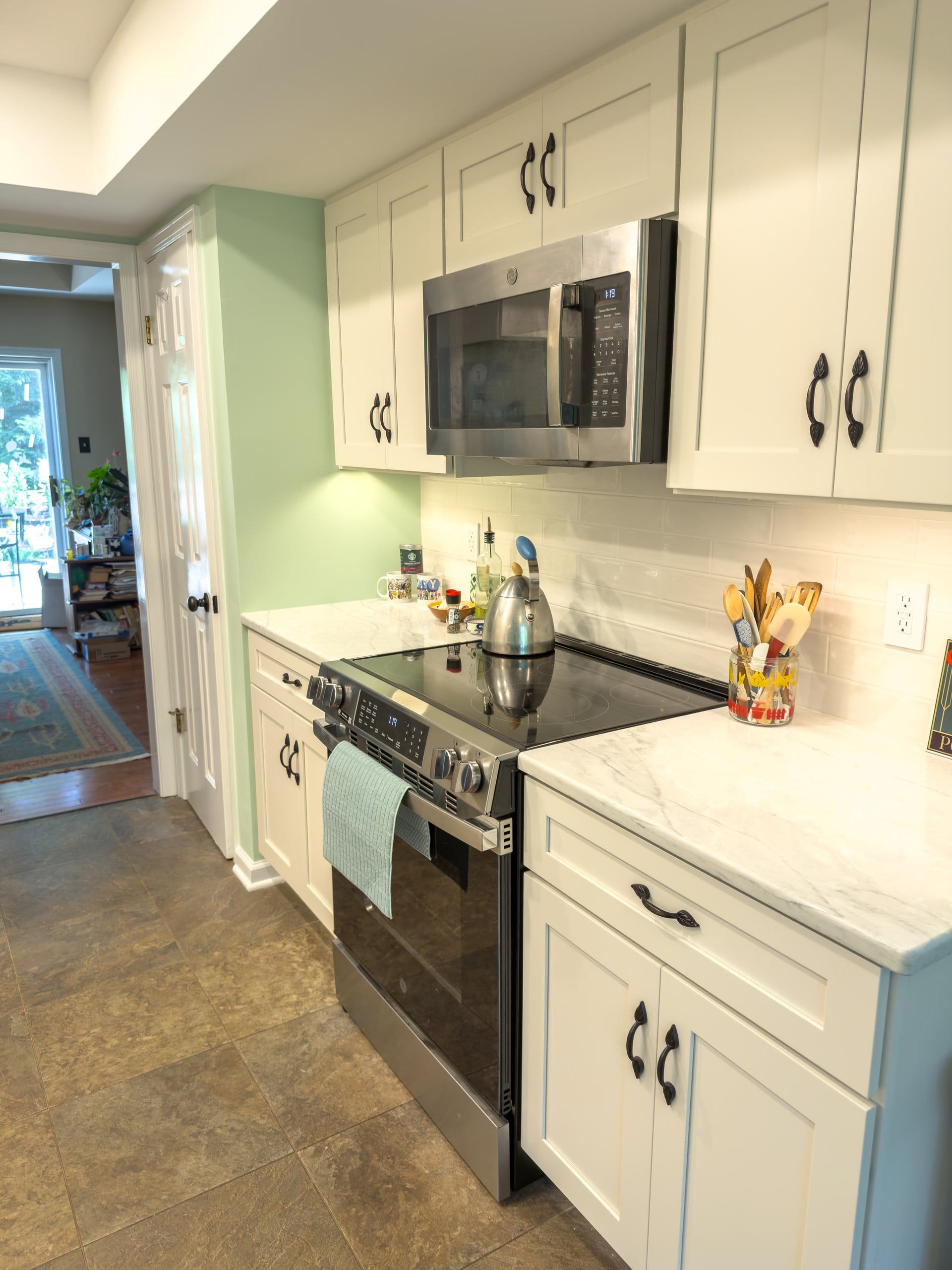 Range wall with white cabinets, subway tile, and a Sleepy Hollow green accent wall