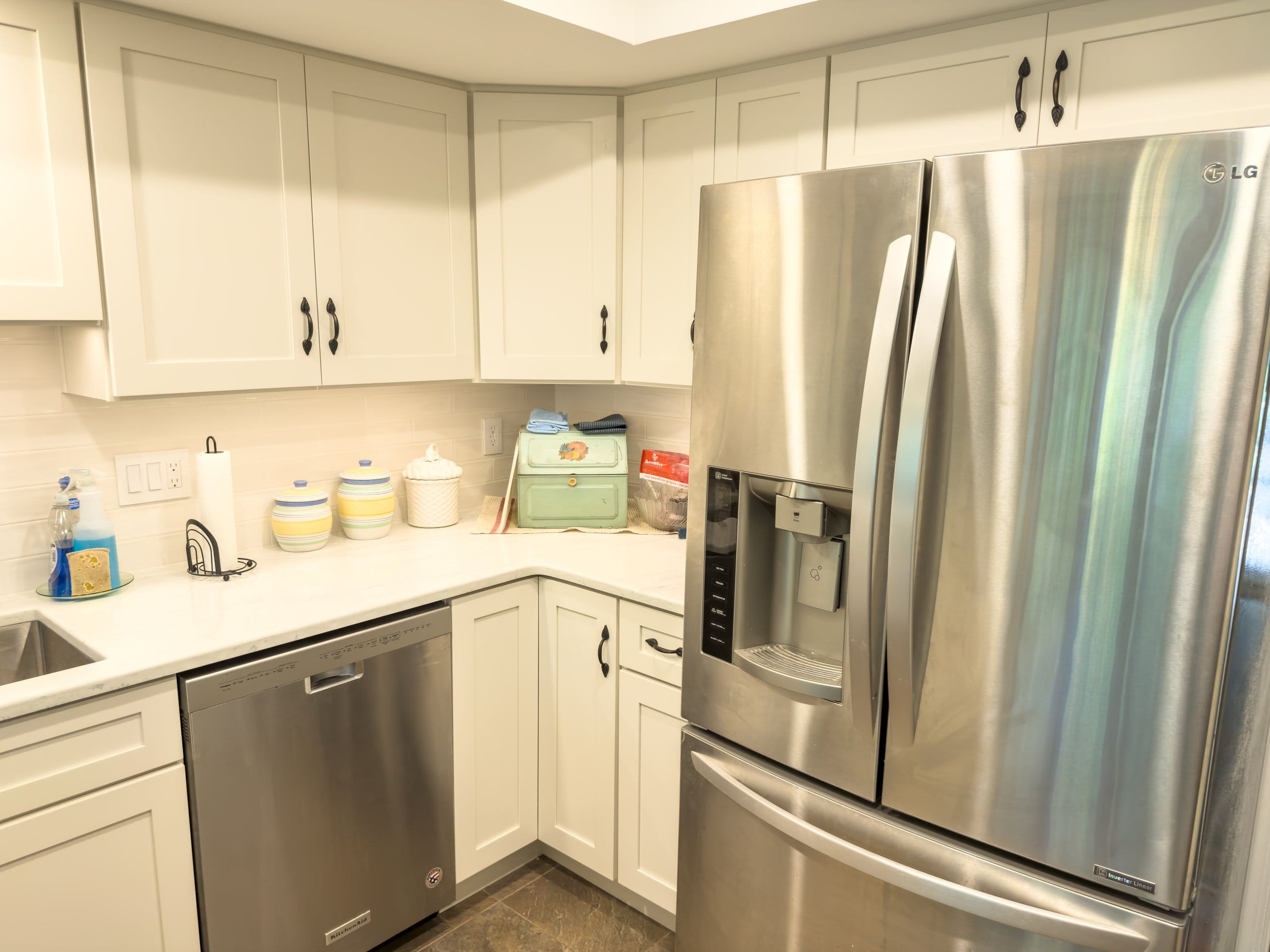 Stainless French-door refrigerator beside white Shaker cabinetry